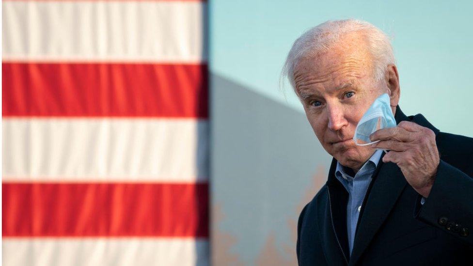 Biden holds his mask in his hand at a rally in Minneapolis