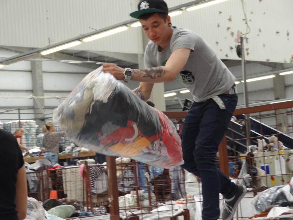 Man in cap flings bag full of old clothes