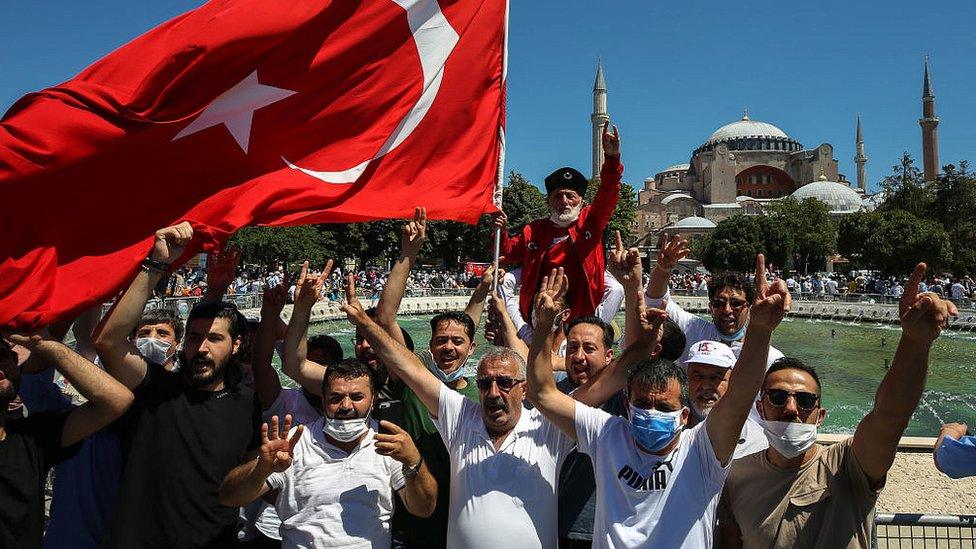 A man waves a Turkish flag as people gather around the Hagia Sophia Mosque ahead of Friday prayer, performed for the first time in 86 years on July 24, 2020 in Istanbul