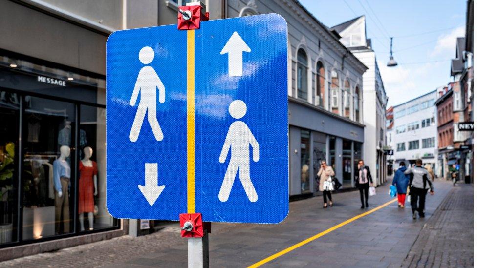 A yellow stripe is painted in the middle of a pedestrian street to help people comply with the social distance guidelines