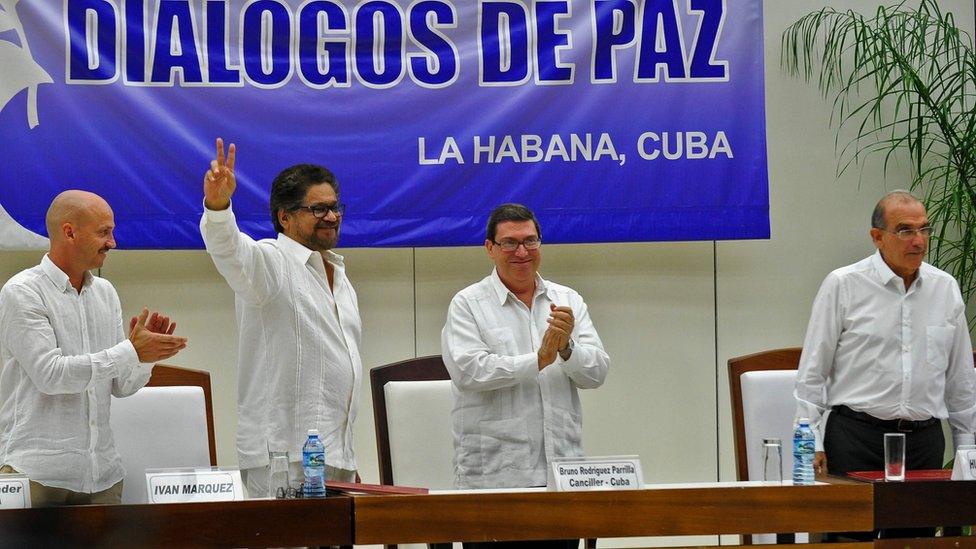 Commander Ivan Marquez flashes the V sign after the signing of the agreement at the conclusion of the peace talks at the Convention Palace in Havana, on August 24, 2016, next to Norway's guarantor for the peace talks, Dag Nylander Cuban Foreign Minister Bruno Rodriguez and Colombian government head of delegation Humberto de la Calle (R).