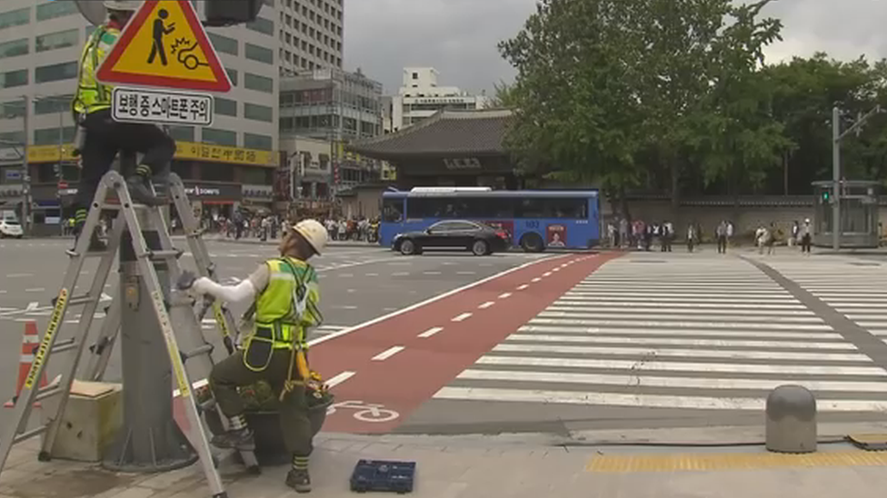 Workmen installing one of the signs at a major pedestrian crossing