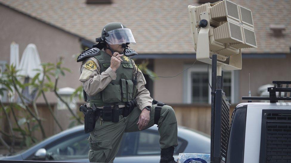 Man in riot police gear behind speaker device