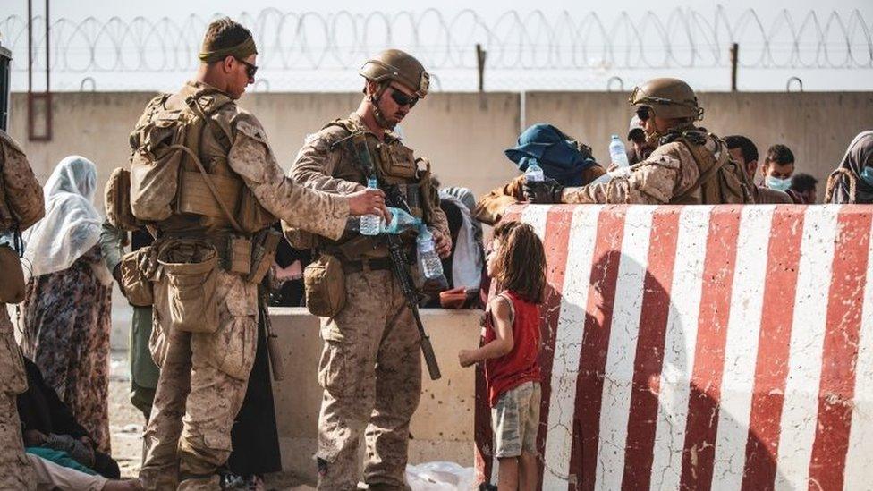 U.S. Marine hand out water during an evacuation at Hamid Karzai International Airport