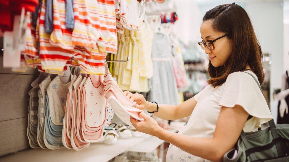 Woman browsing baby clothes in a shop.