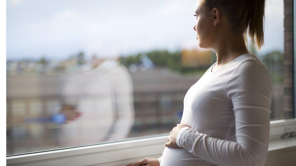 Pregnant woman looking out the window