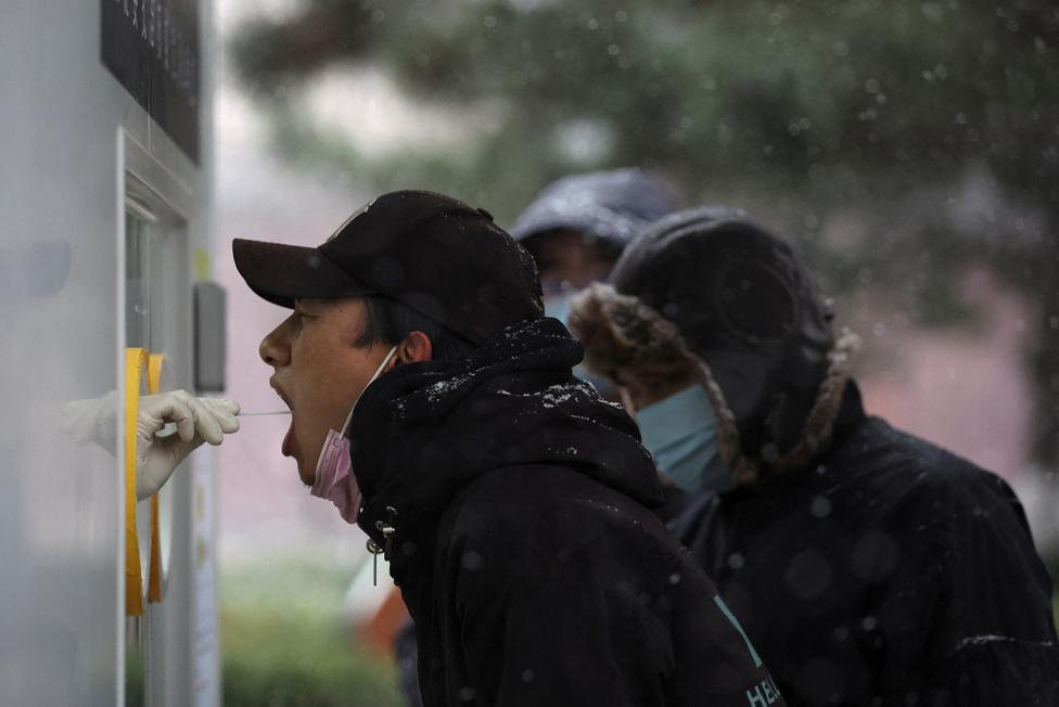 A man has his swab sample taken at a mobile nucleic acid testing site, following the coronavirus disease (Covid-19) outbreak, on a snowy day in Beijing, China.