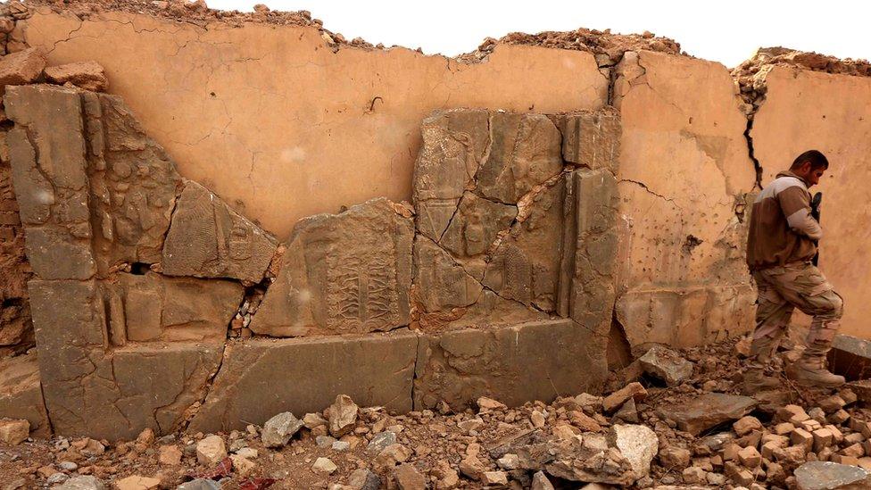 A soldier walks past a smashed artefact at Nimrud