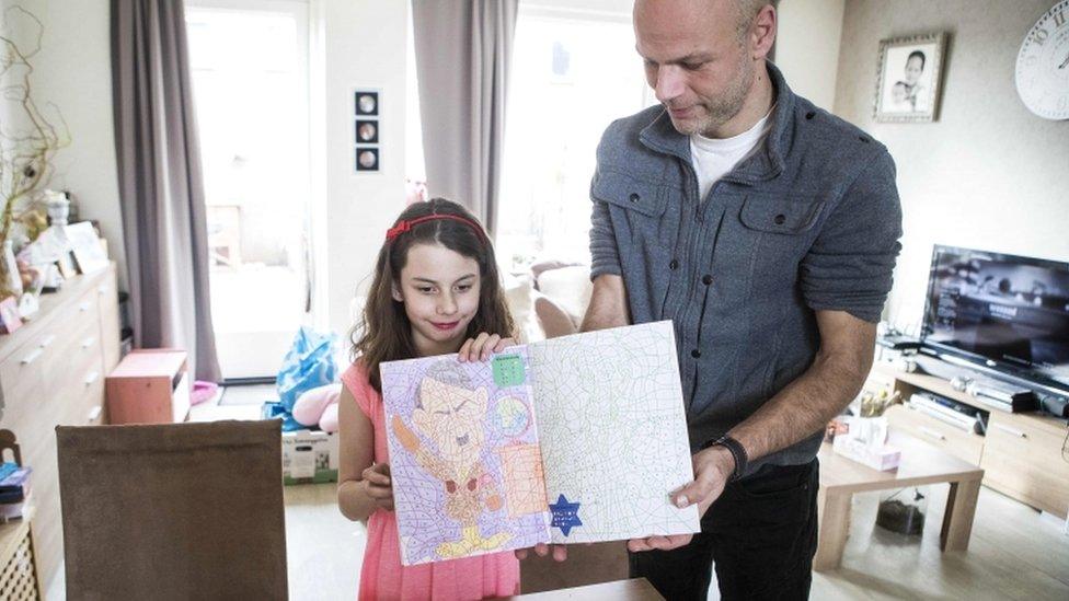 Ray Vervloed (R) and his daughter Kira pose with a colouring book with an image of Adolf Hitler bought at the Dutch store Kruidvat in Pijnacker, the Netherlands