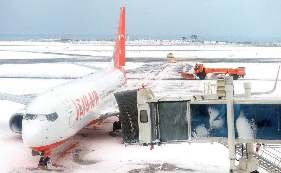 A general view shows a Jeju airlines Boeing 737 aircraft parked amid snow coverage at Jeju airport on 25 January 2015