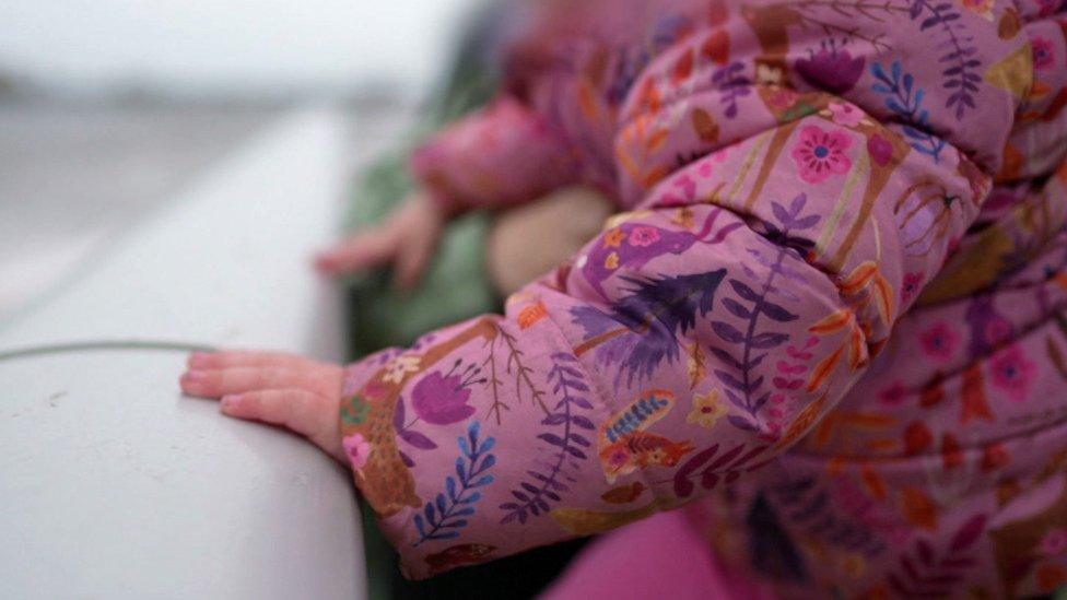 Shot of a little girl's hands holding on to a rail by the sea