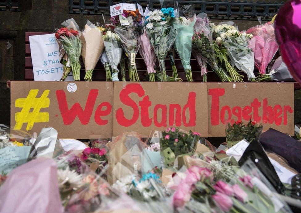 Sign with flowers saying We Stand Together