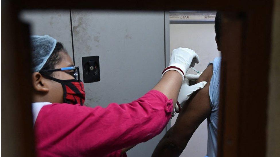 A health worker inoculates a man with a dose of Covaxin Covid-19 coronavirus vaccine