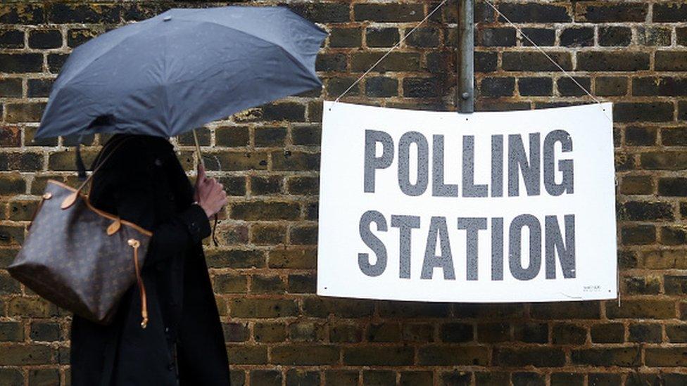 Woman with umbrella outside polling station