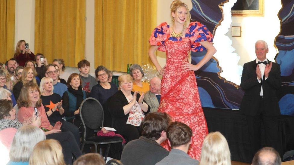 A woman in a red and blue dress on a runway