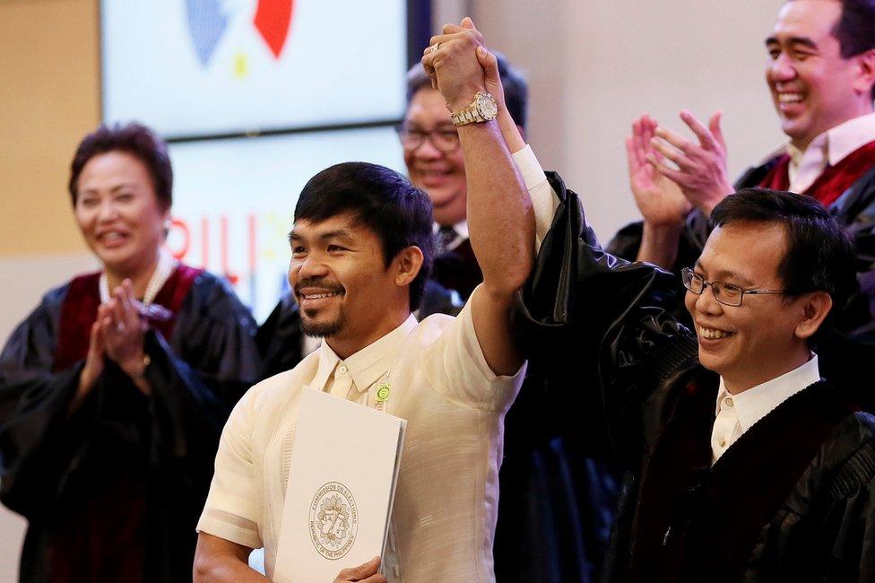 Manny Pacquiao holds his Certificate of Canvass as he is proclaimed the Seventh Senator by Commissioner Christopher Lim, right, and surrounded by other officials, at the Commission on Elections, 19 May 2016 in Pasay City.