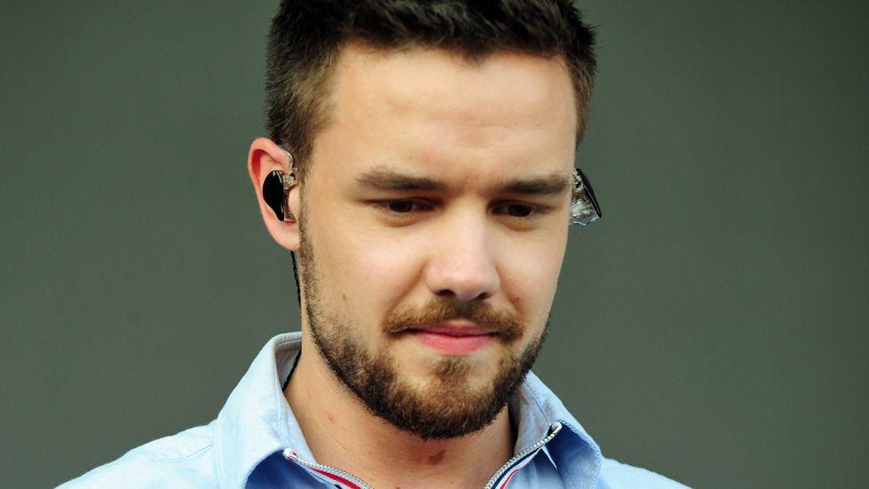 Liam Payne looking down with an earpiece in on stage in 2018