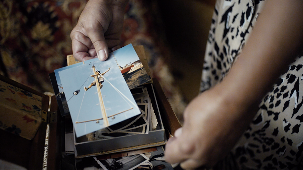 Carlotta holds a photograph of her climbing the mast of her sailing boat