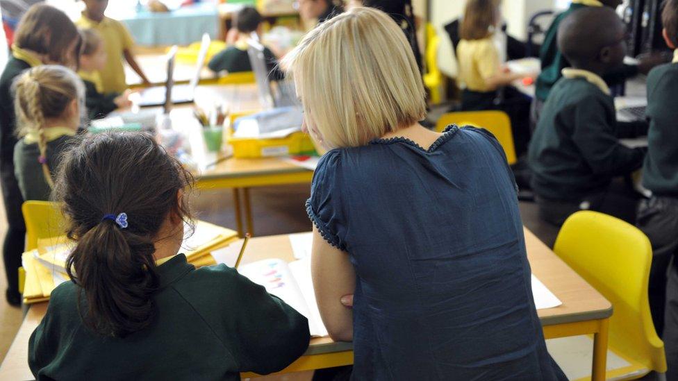 A female teacher helps a young girl