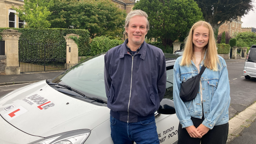 Driving instructor Marcus Sheppard and newly qualified driver Poppy Allen standing next to a car