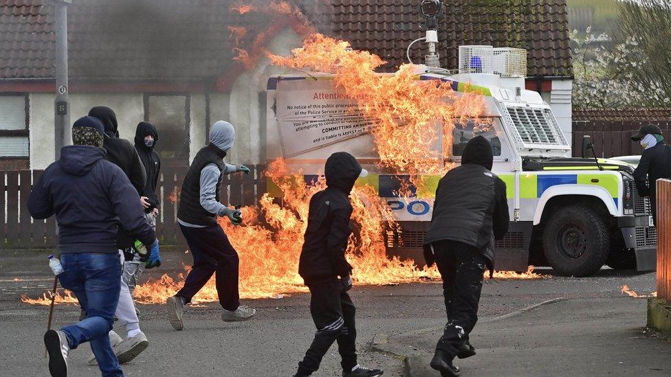 Young hooded men prepare to throw a petrol bomb at police vehicle in Londonderry.