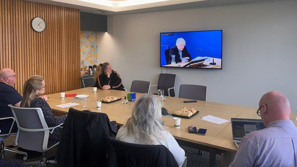 Individuals gathered to watch Boris Johnson give evidence