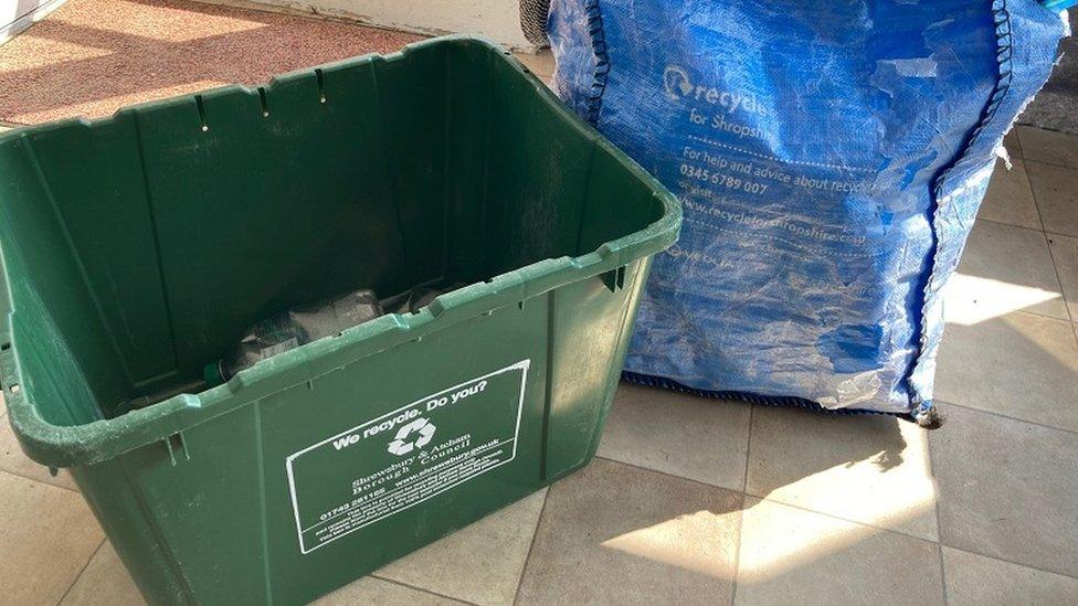 Box for recycling plastic, glass and metal alongside a blue bag for cardboard and paper