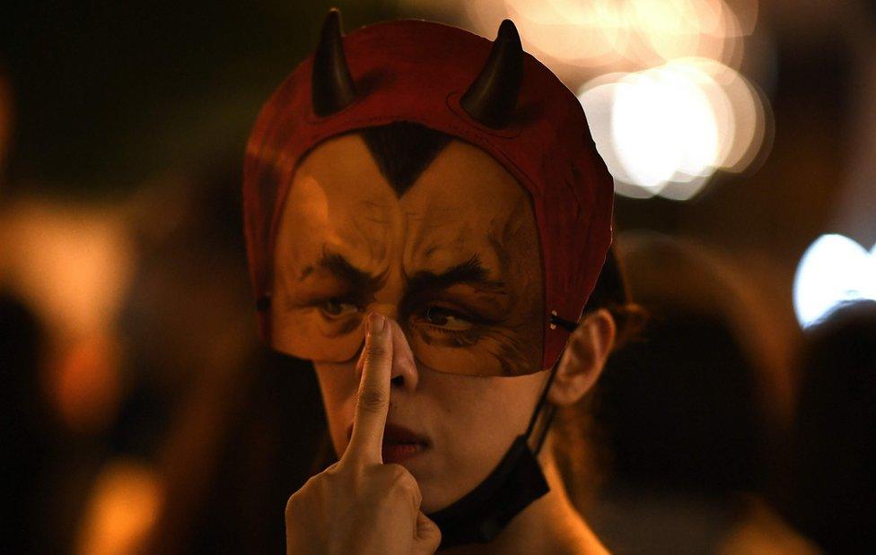 A protester wearing a facemask gestures while people gather in the Admiralty area of Hong Kong