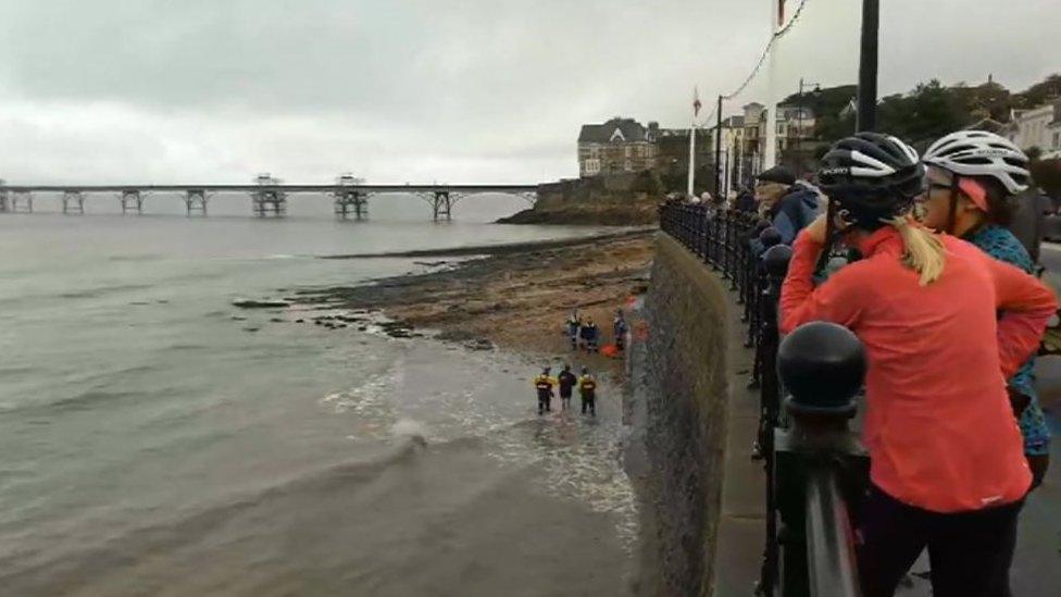 A picture showing a crowd gathering to watch a man be rescued