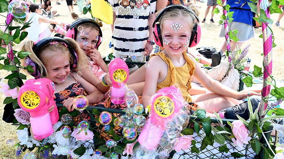 Children in a trolley cart with bubble-guns play at Latitude