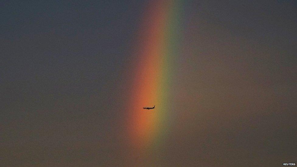 An airplane flies past a rainbow at dusk in Beijing, China on 3 August, 2015