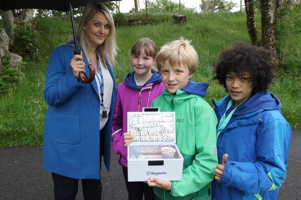 A woman and three children holding an insulated box