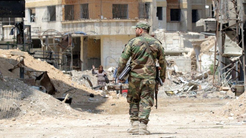 Syrian soldiers walk amongst destruction in the countryside of Damascus, Syria in 2018