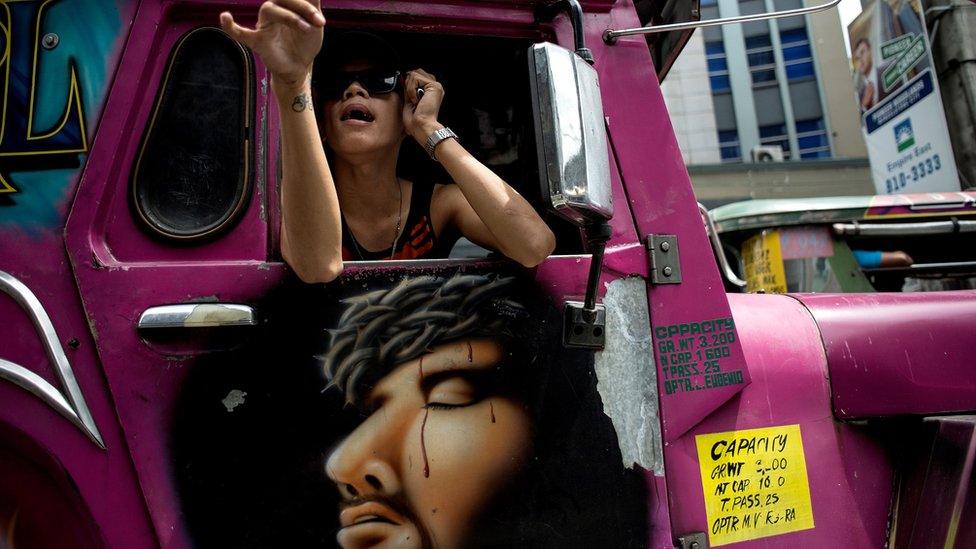 A jeepney driver's assistant calls for passengers at a busy street in Manila