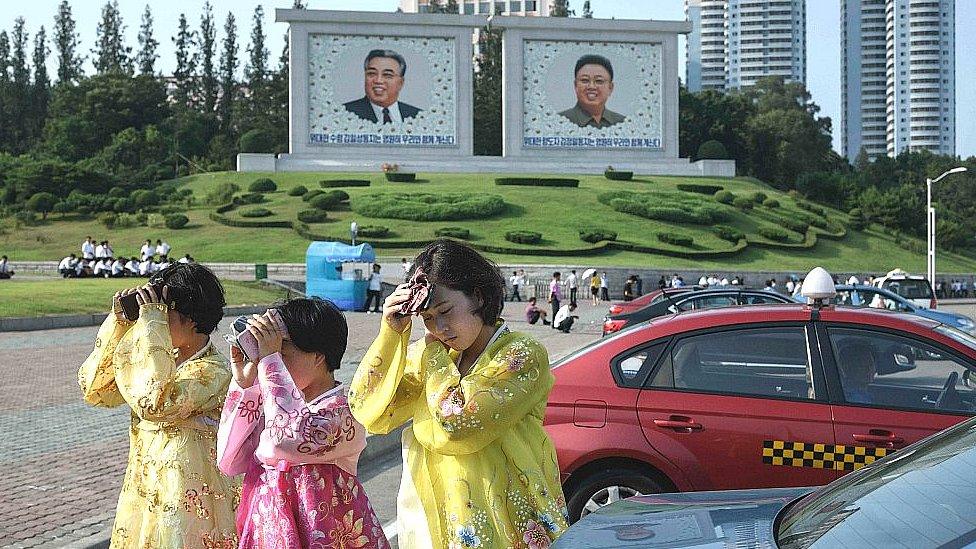 Women in Pyongyang try to protect their faces from the sun. 27 July 2018