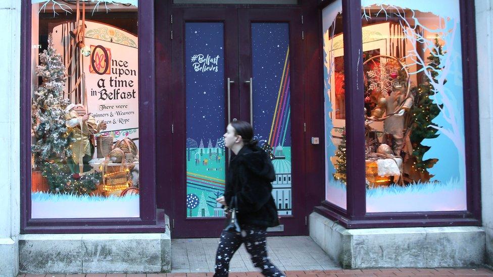 A woman walks past a closed shop in Belfast