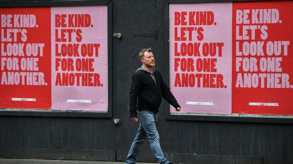 Man in front of 'Be Kind' posters