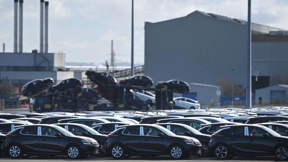 Cars outside of a manufacturing plant.