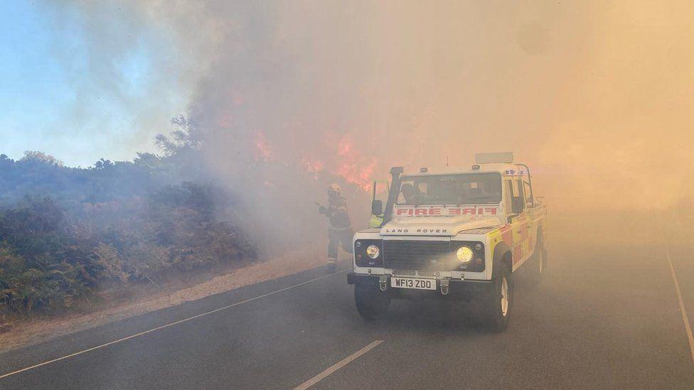 A firefighter running next to a fire truck to extinguish a blaze in Dorset