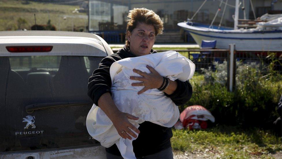 A woman holds the wrapped body of a migrant baby girl, who was said to have been on board a wooden boat carrying refugees and migrants that sank near Lesbos on 28 October (30 October 2015)