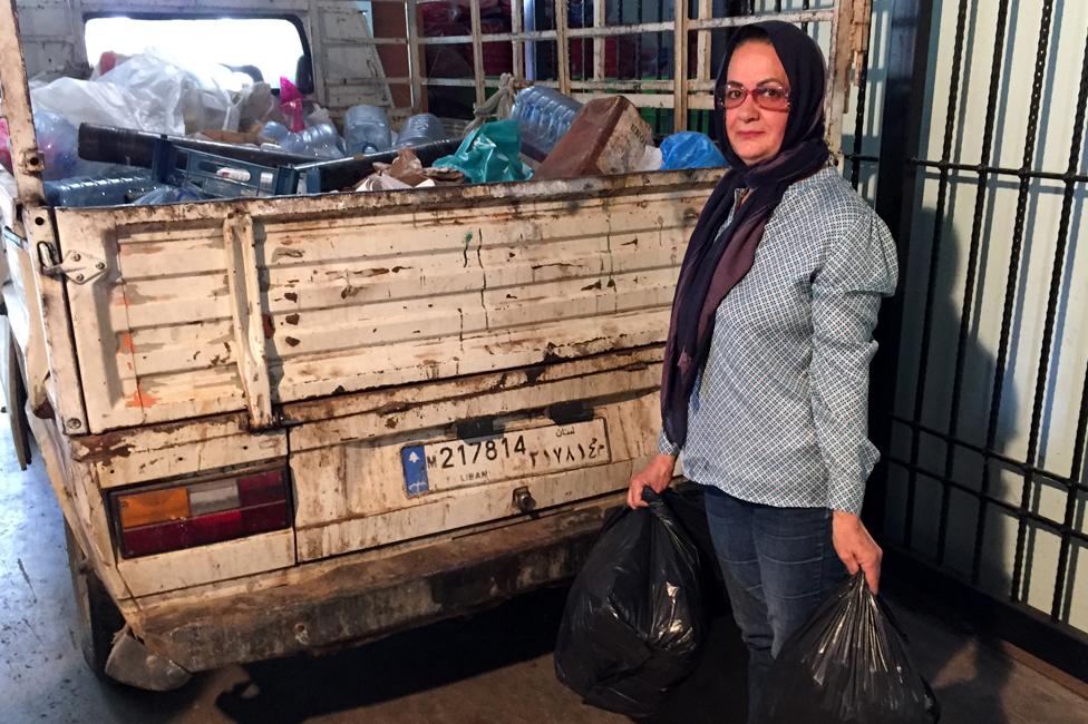 Khadija Farhat holding rubbish bags, standing next to a lorry