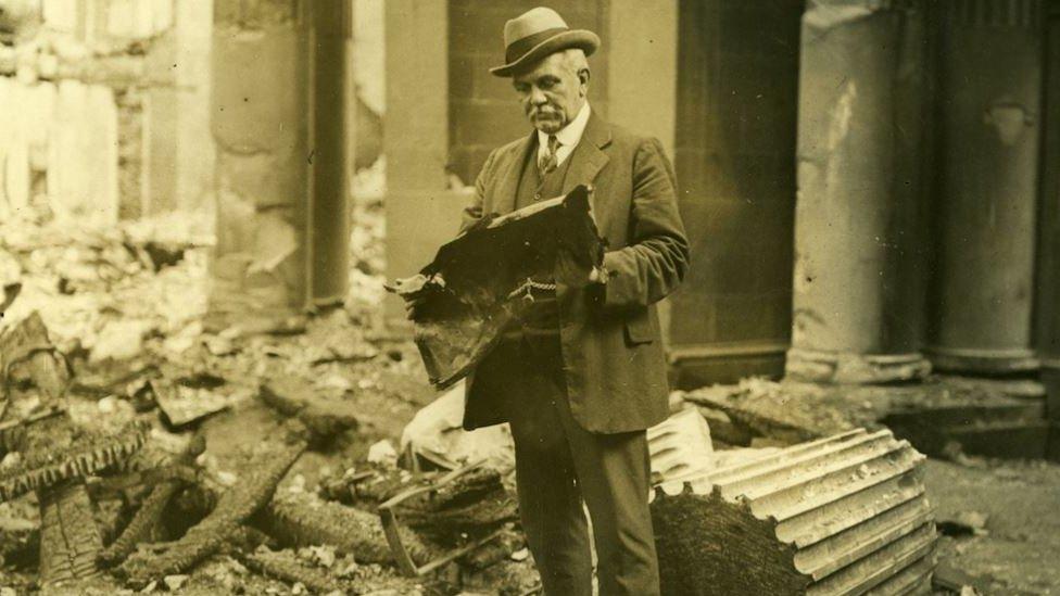 A man looks at a damaged document found in the rubble after the first at the Four Courts in Dublin in 1922