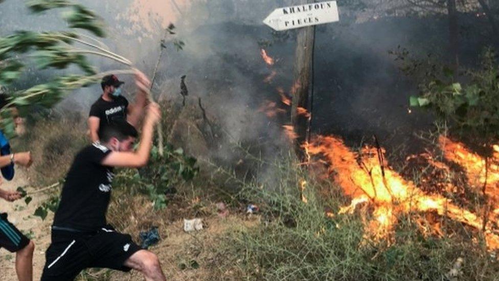 People attempt to put out a fire in the mountainous Tizi Ouzou province, east of Algiers, Algeria August 10, 2021