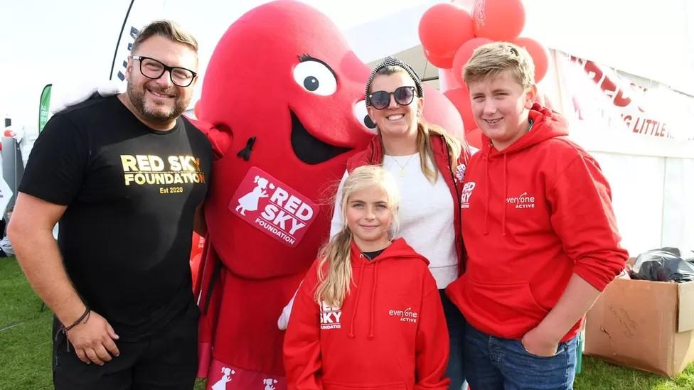 Sergio Petrucci with wife, Emma and children Luna and Enzo. They are pictured with a Red Sky heart mascot