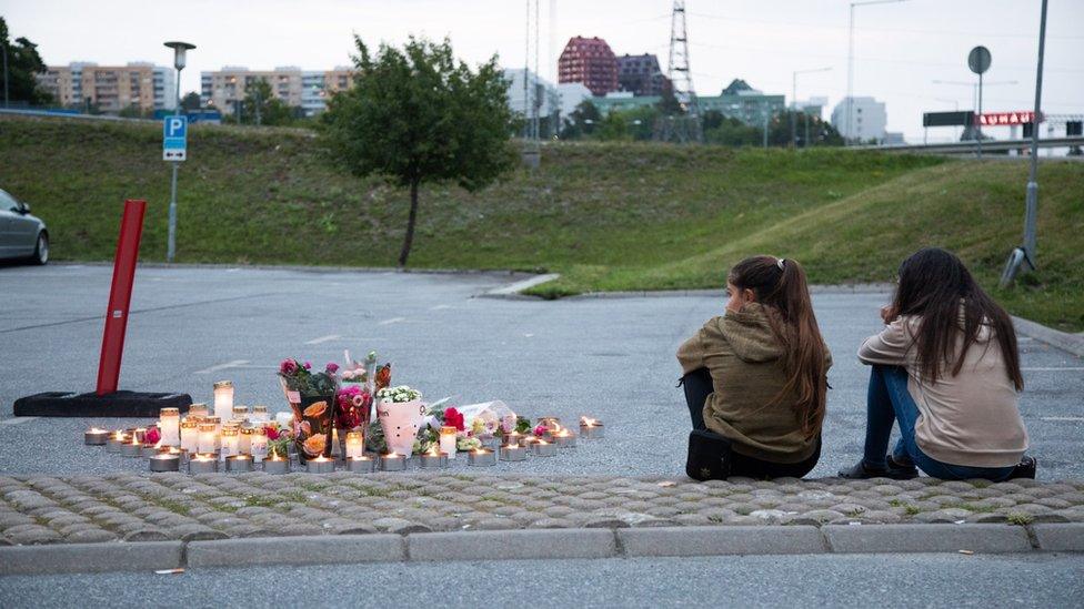 People lay candles and flowers at the site where a twelve year old girl was shot near a petrol station in Botkyrka, south of Stockholm, Sweden, 03 August 2020.