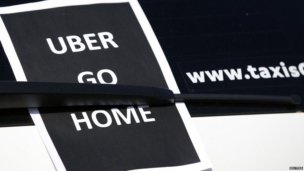 A leaflet which reads "Uber go home" is seen on a taxi in France