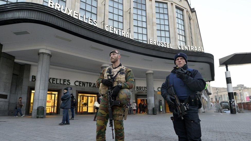 An armed Belgian policeman and soldier stand guard outside the central station in Brussels