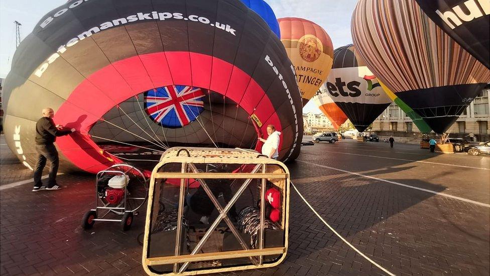 Flight staff inflating a black and red hot air balloon