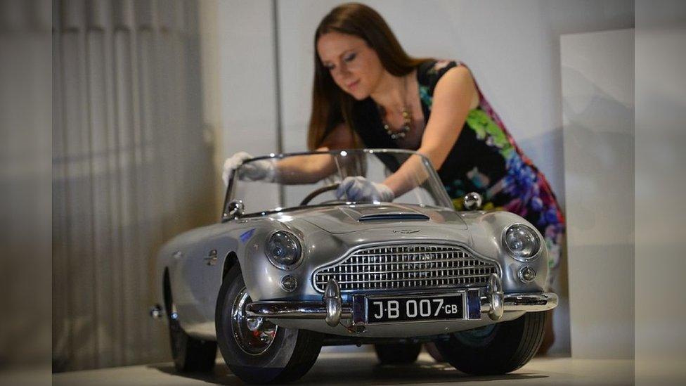 A member of staff poses for photographers with a miniature James Bond DB5 presented to Britain's Prince Andrew by the Aston Martin company in 1965, at Buckingham Palace in central London on July 24, 2014