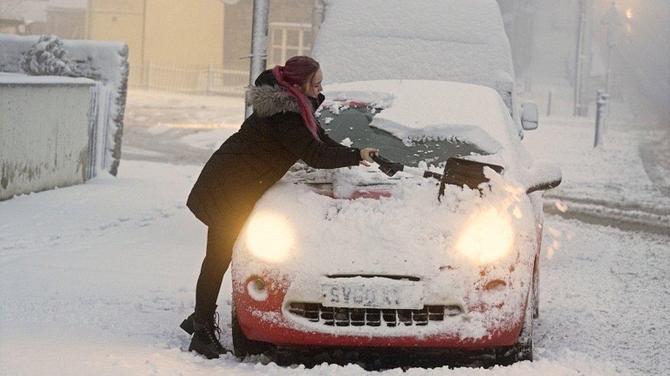 Woman clears snow off car in County Durham